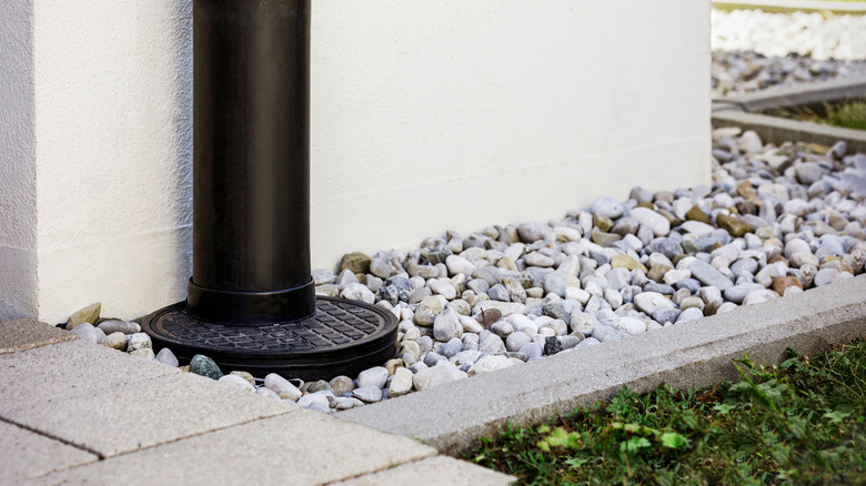 Downpipe going into a French drain along the outside of  home with green turf in the foreground