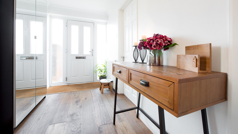 A wooden table with drawers near entryway