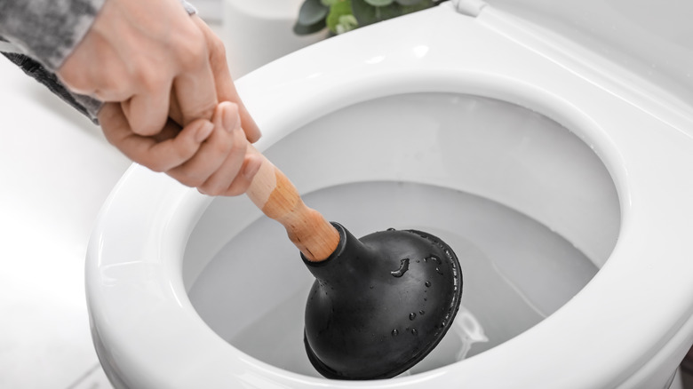 person using toilet plunger