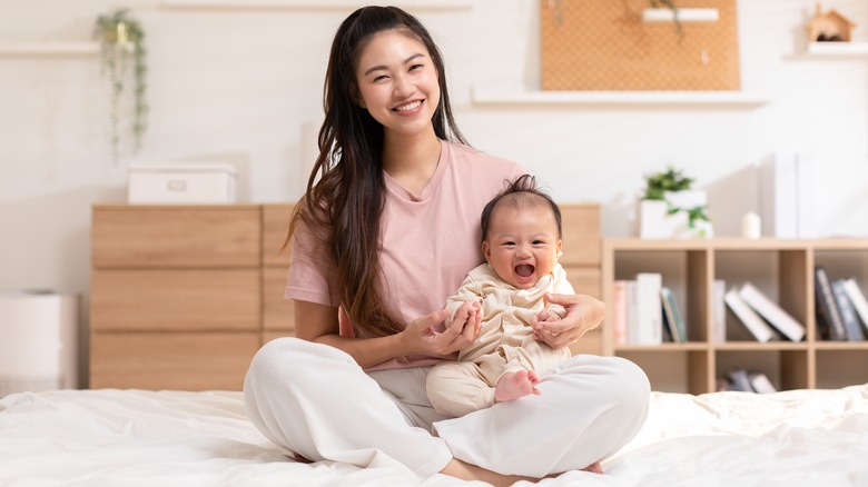 mom holding baby on bed