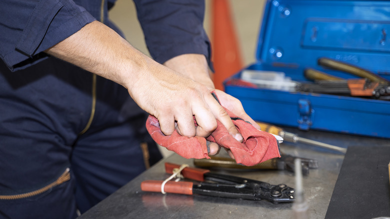 Close up of a person cleaning their tools with a rag