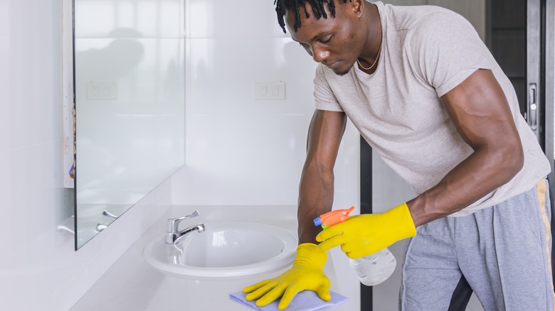 man cleaning bathroom sink and counter
