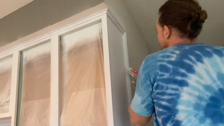 man caulking around kitchen cabinets