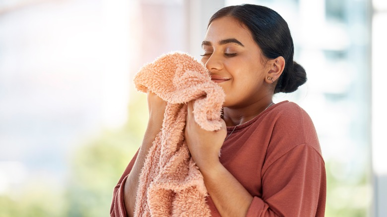 young woman smelling fluffy towel