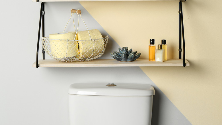 Wire basket with toilet paper rolls inside, knickknacks placed on the shelf next to and above it