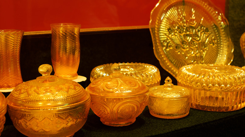 collection of marigold carnival glass with covered bowls, cups, and plates