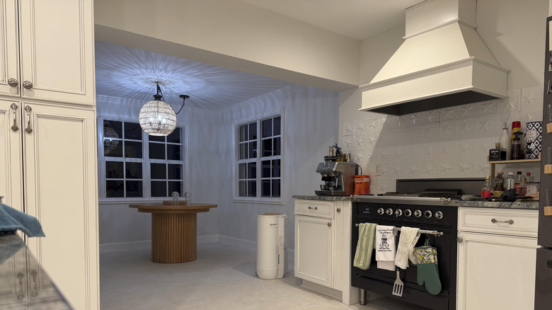 A statement range hood in a cream tone over cream cabinets and a tin panel backsplash