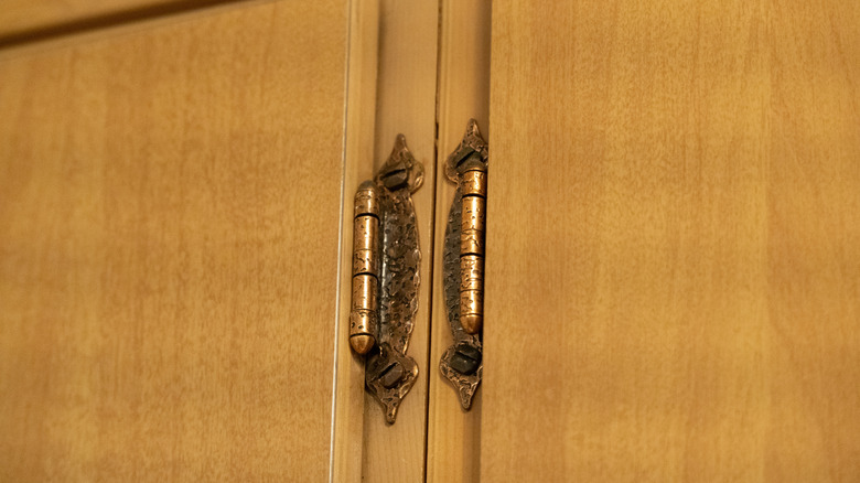 Antique brass hinges on wooden kitchen cabinets