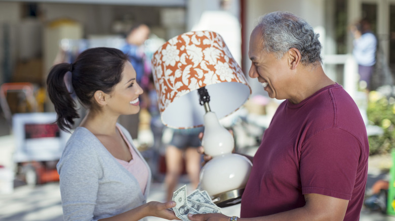 Man and woman completing a transaction of a lamp at a garage sale
