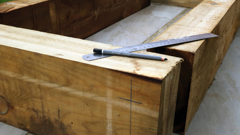 railroad ties standing ready to make a garden bed with a rule and pencil on top