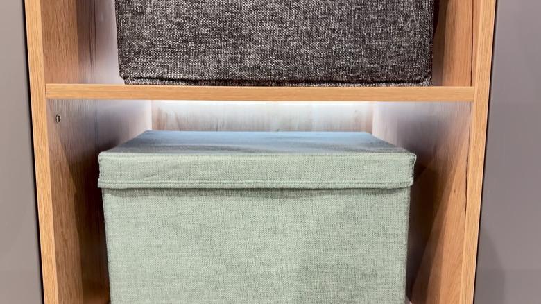Closeup of a green fabric bin in a wooden shelf system