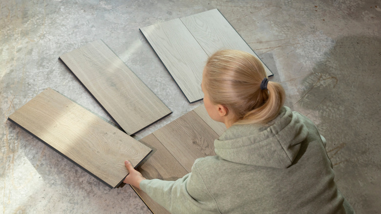 A person comparing vinyl samples on concrete subfloor