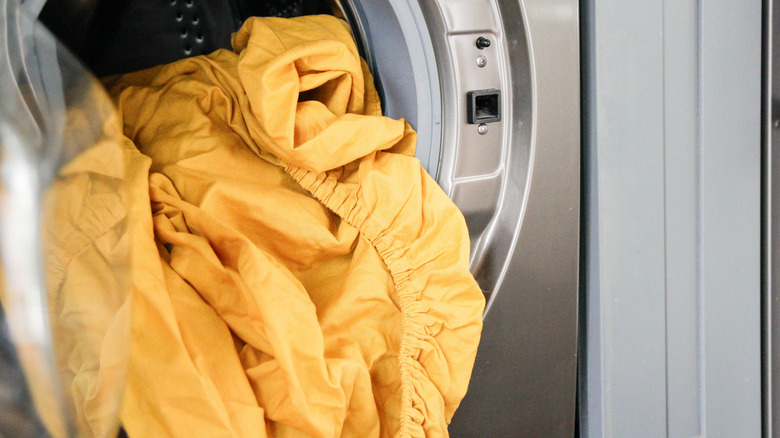 Bright yellow sheets tumbling out of a dryer