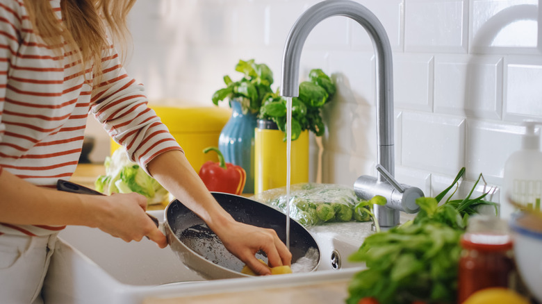 Young woman washes pan