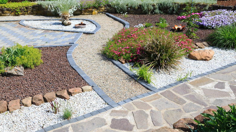 A garden with various hardscaping materials, plants, mulch, gravel, pavers, and flagstone.