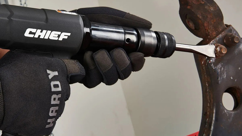 A person's gloved hands using a Chief long-barrel air hammer