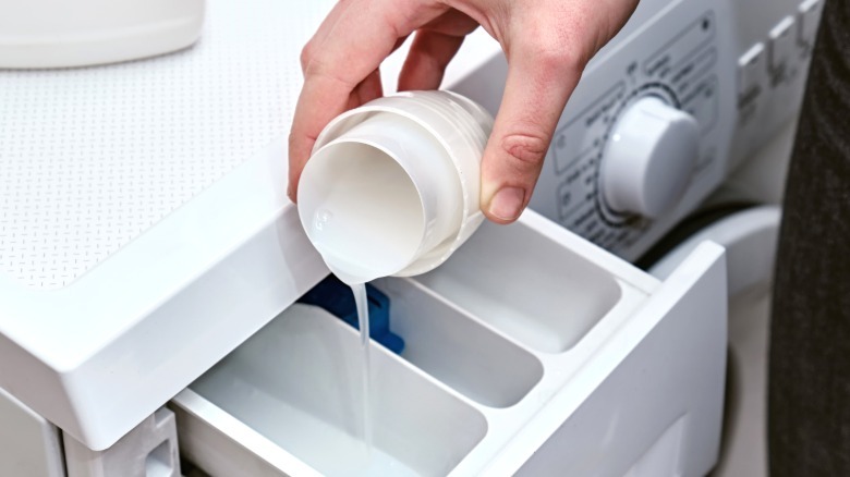 Person pouring laundry detergent in washing machine dispenser