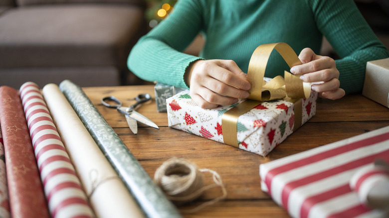 Close-up of person wrapping Christmas gifts with holiday wrapping paper