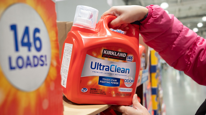 Woman's arms taking Kirkland Ultra Clean detergent off shelf