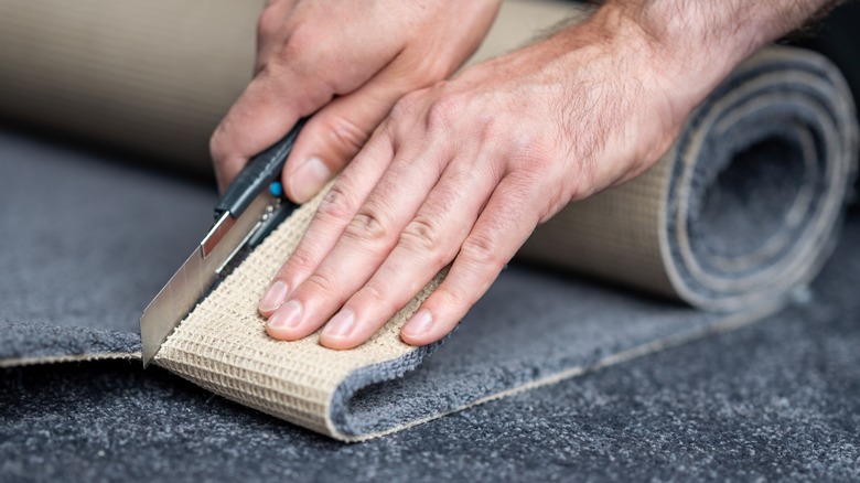 man cutting gray carpet 