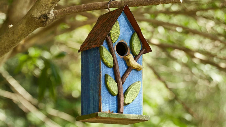 Glitzhome's 9.7-inch Rustic Blue Decorative Bird House hanging from a tree