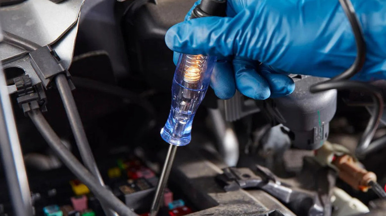 A person using Cen-Tech's 6/12 Volt Circuit Tester on a car