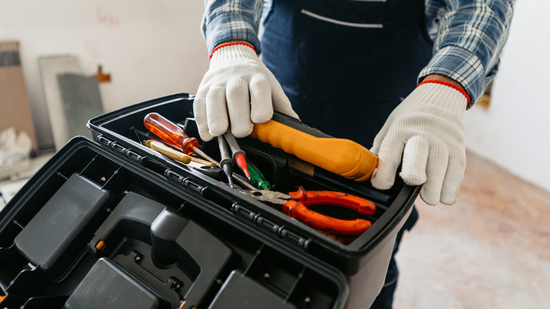 A person putting electrical tools back into a toolbox