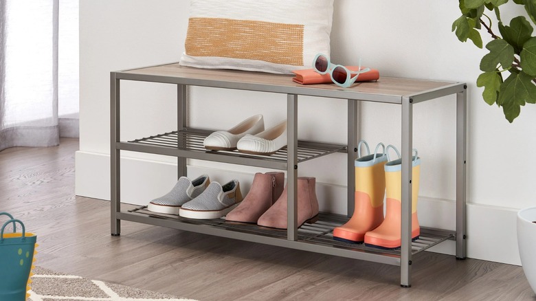 Trinity Shoe Bench with Boot Storage in entryway loaded with shoes and topped with a pillow, sunglasses, and a book