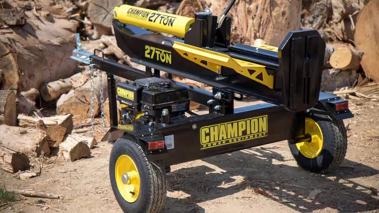 A Champion Power Equipment 27 Ton Gas Powered Hydraulic Wood Log Splitter sits near several split logs on the ground