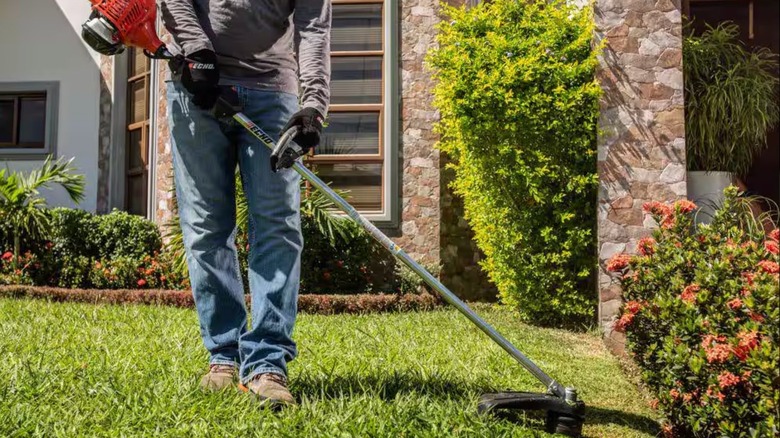 A man uses an ECHO Gas Straight Shaft String Trimmer to edge a yard