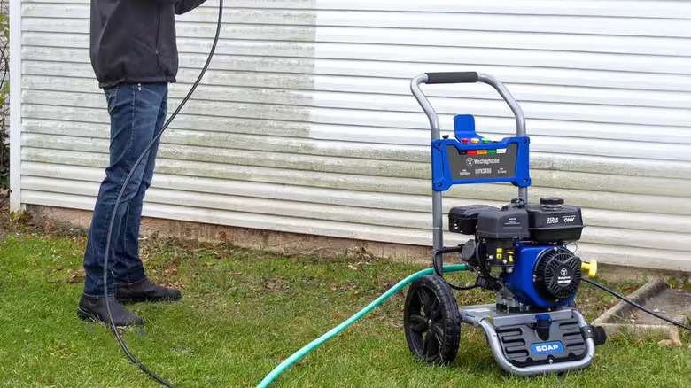 A man uses a Westinghouse 3400 PSI Pressure Washer to clean dirty siding