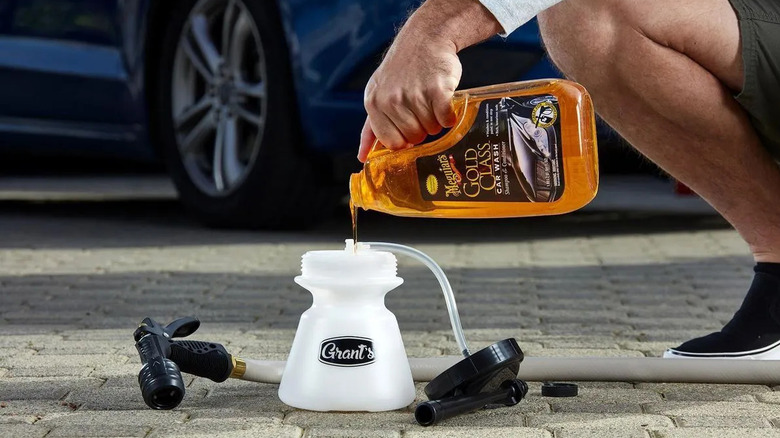 Person pouring car wash solution into a foaming spray gun