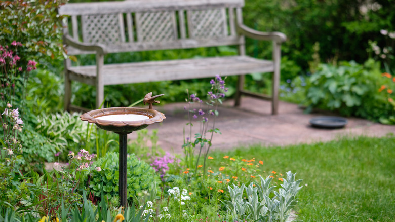 Idyllic garden scene with flowers, a bench, and a birdbath