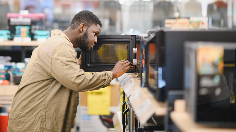 A man shopping for a microwave in a store