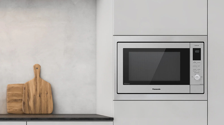 Panasonic HomeChef 4-in-1 microwave installed in a cabinet wall next to a counter with cutting boards on it
