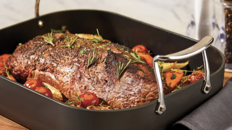 A roasting pan with a roast and veggies in it