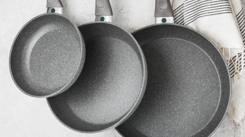 Three frying pans hanging on a wall from small to large