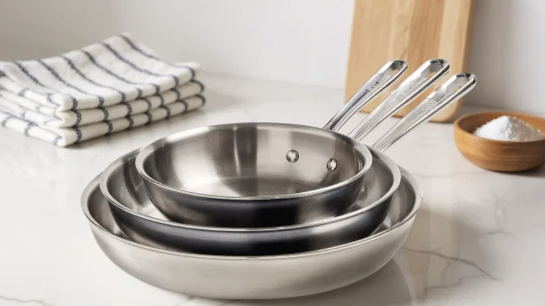 Three, clean silver frying pans stacked from small to large