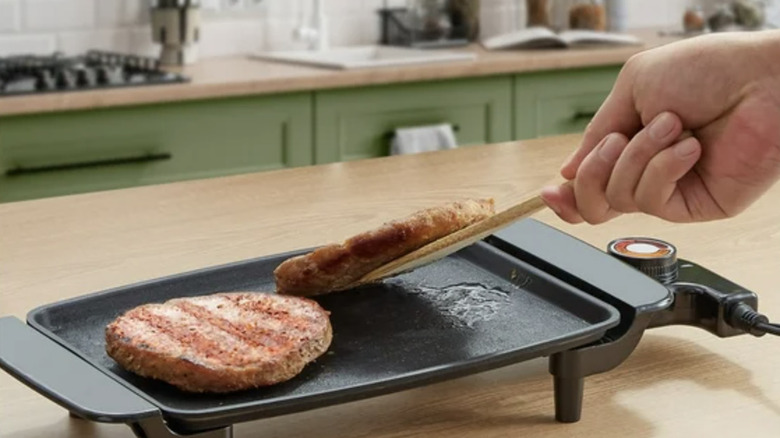 Hand flipping burgers on a small Elite Cuisine griddle