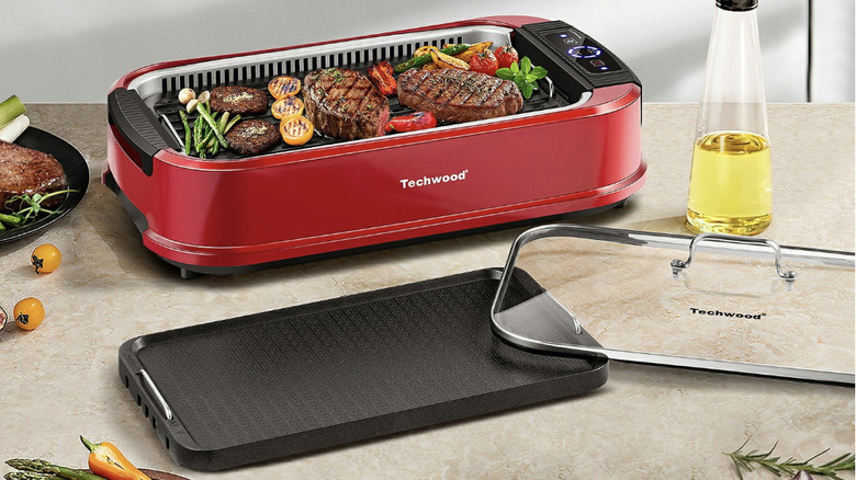 Techwood griddle on a counter with lid and alternative cooking plate with meats and veggies
