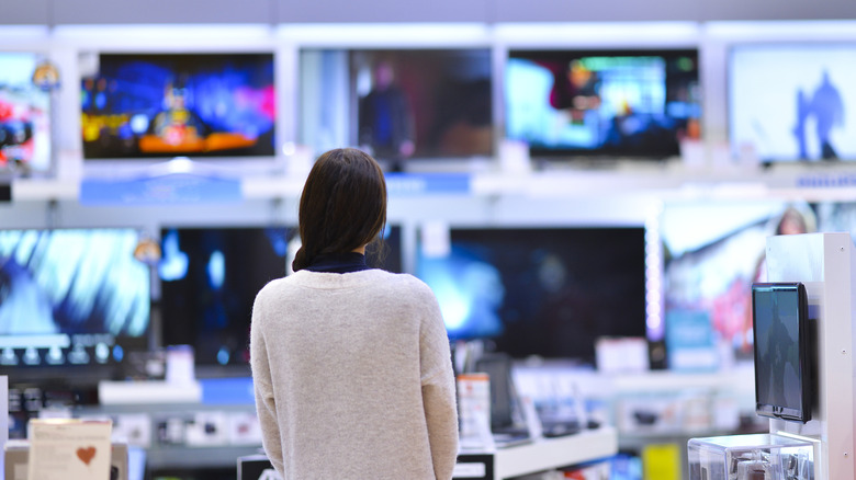 A person looking at a wall of televisions in a store