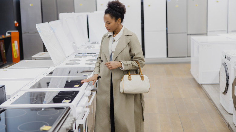 Woman shopping at an appliance store touching an electric range