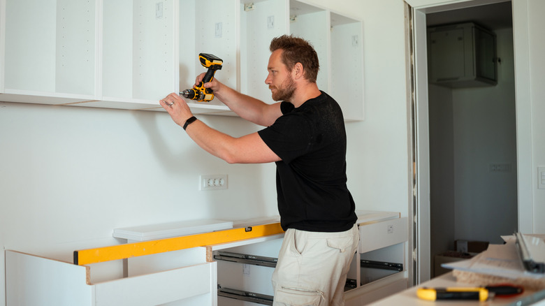 A person installing kitchen cabinets