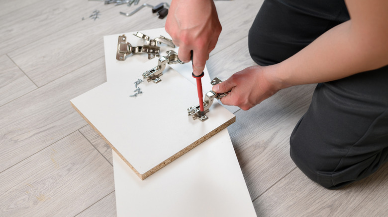 A person attaching a hinge to a ready-to-assemble cabinet door