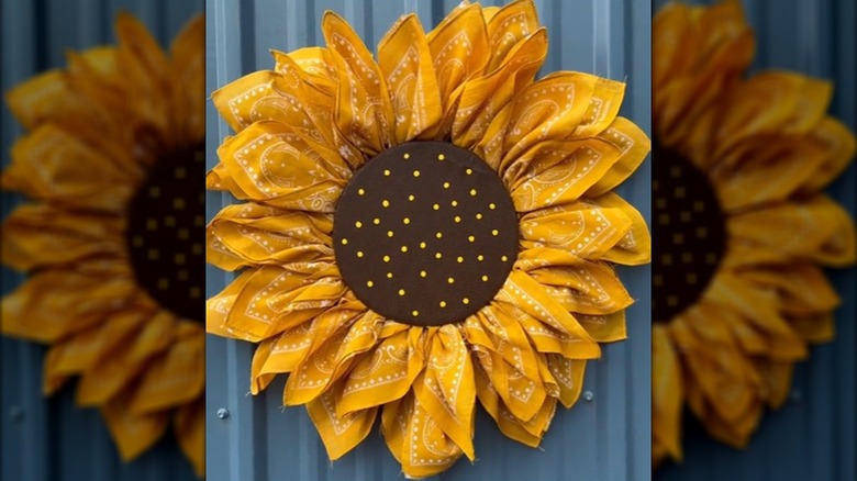A sunflower wall hanging is made from yellow bandanas as petals around a wreath form.