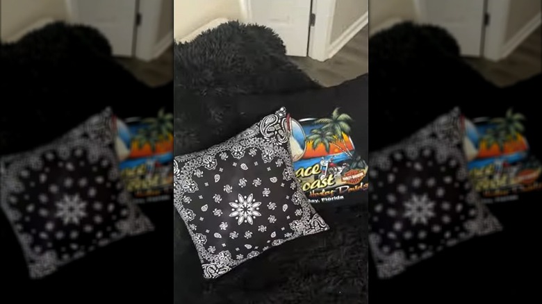 A throw pillow for a couch is made out of two black bandanas, a zipper, and a pillow form