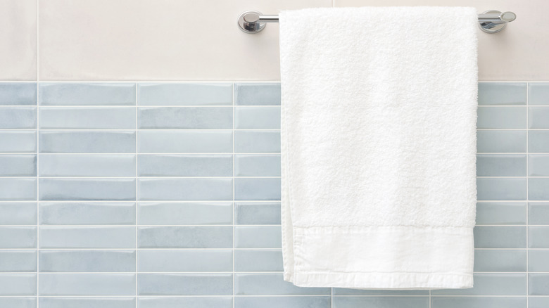 White fluffy bath towel hanging on wall rail in bathroom