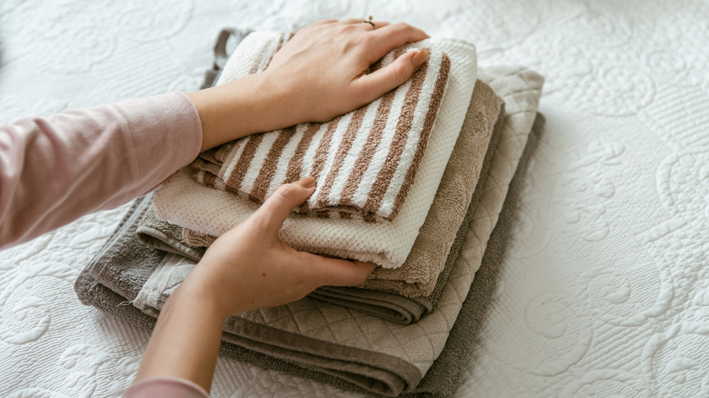 Person folding stack of towels on a bed