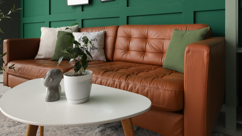 brown leather couch in a living room with emerald green wall paneling