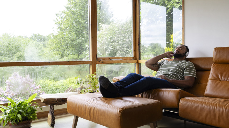 Man reclining on leather sofa with headphones